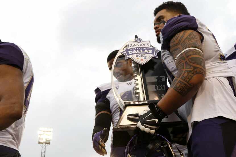 Washington Huskies players take their trophy off the stage after winning Zaxby's Heart of...