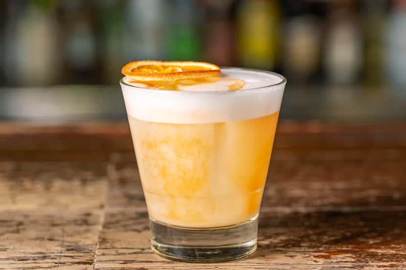 Vanilla sour cocktail in glass on dark wood bar