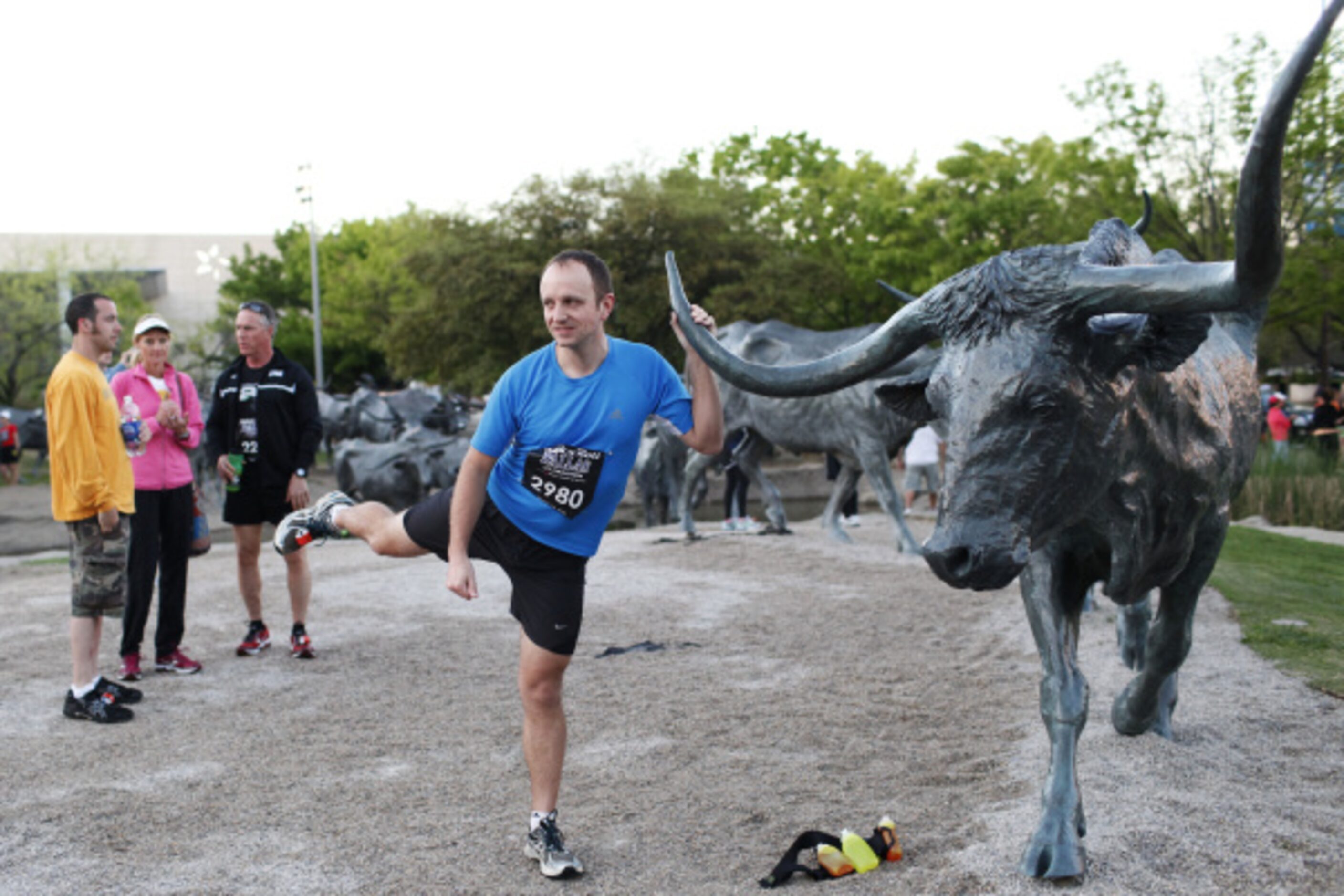 Neil Decker stretches his legs with the help of a cattle sculpture in Dallas Pioneer Plaza...