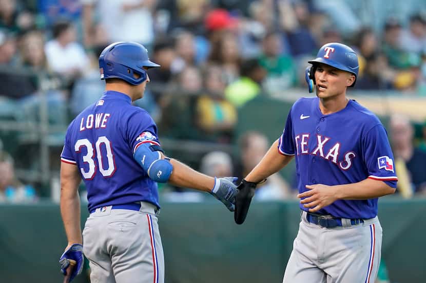 Texas Rangers' Corey Seager (5) celebrates with Nathaniel Lowe (30) after scoring on a...