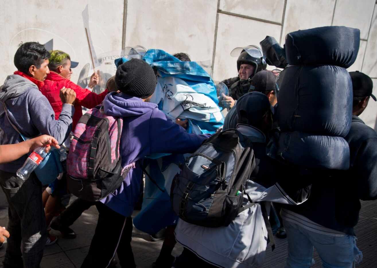 Migrants push past Mexican police at the Chaparral border crossing in Tijuana on Nov. 25,...