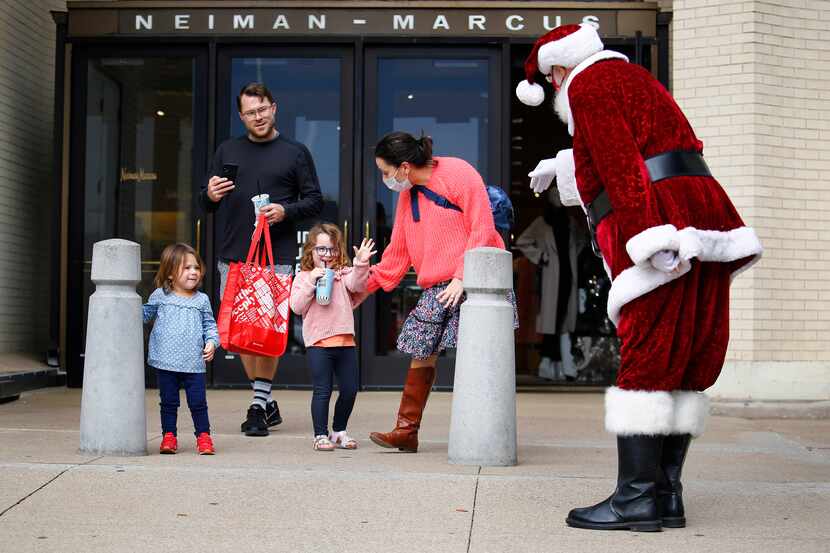 Stella Helt, 4, waves to Santa Claus, aka Mike Davis, as she and her sister, Evie, dad Bob...