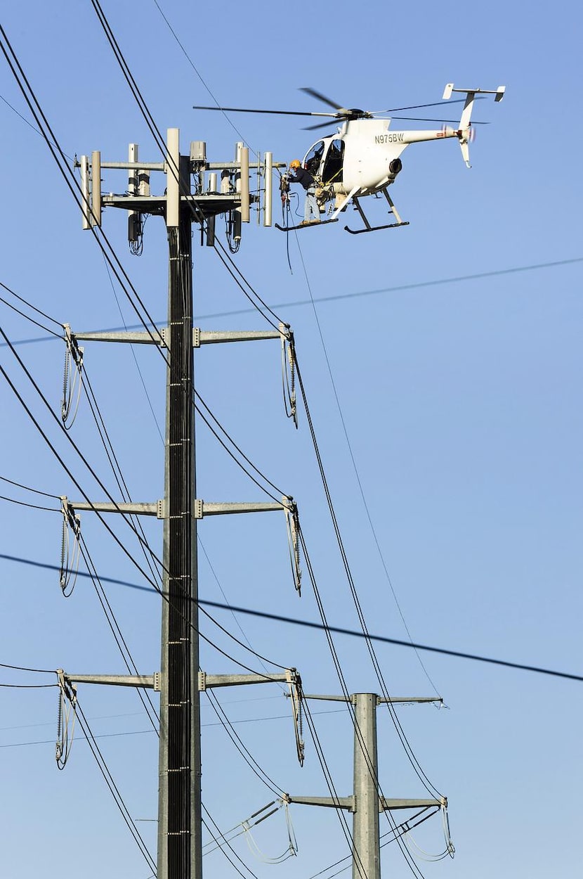 Helicopter linemen  for an Oncor Electric Delivery contractor worked on transmission lines...