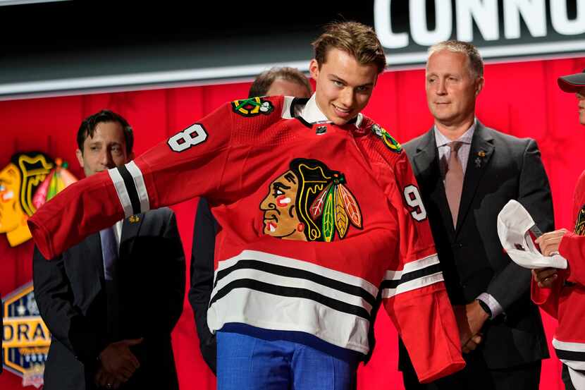 Chicago Blackhawks first round draft pick Connor Bedard puts on his jersey after being...