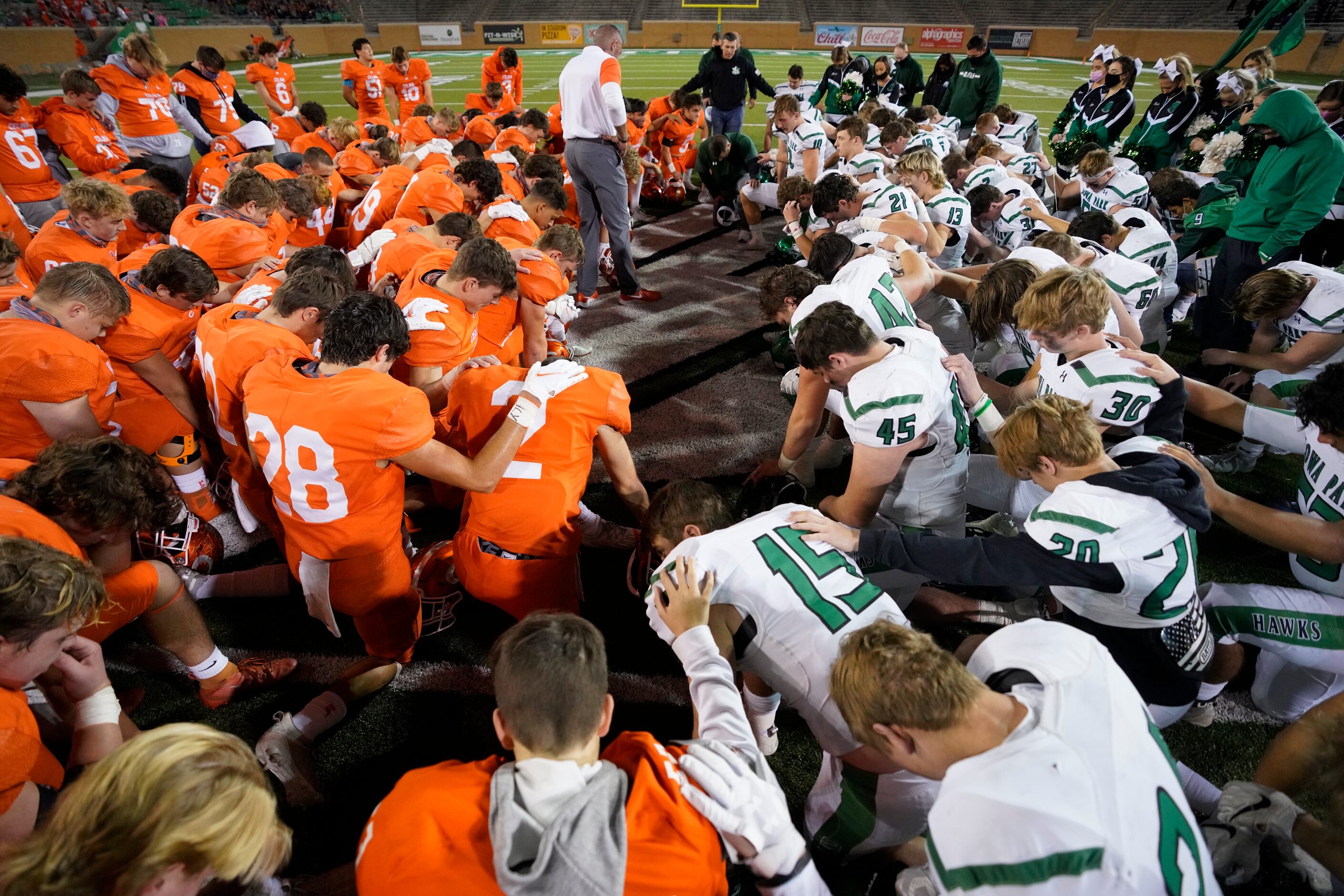 Celina (left) and Iowa Park players kneel in prayer together at midfield after Celina’s...