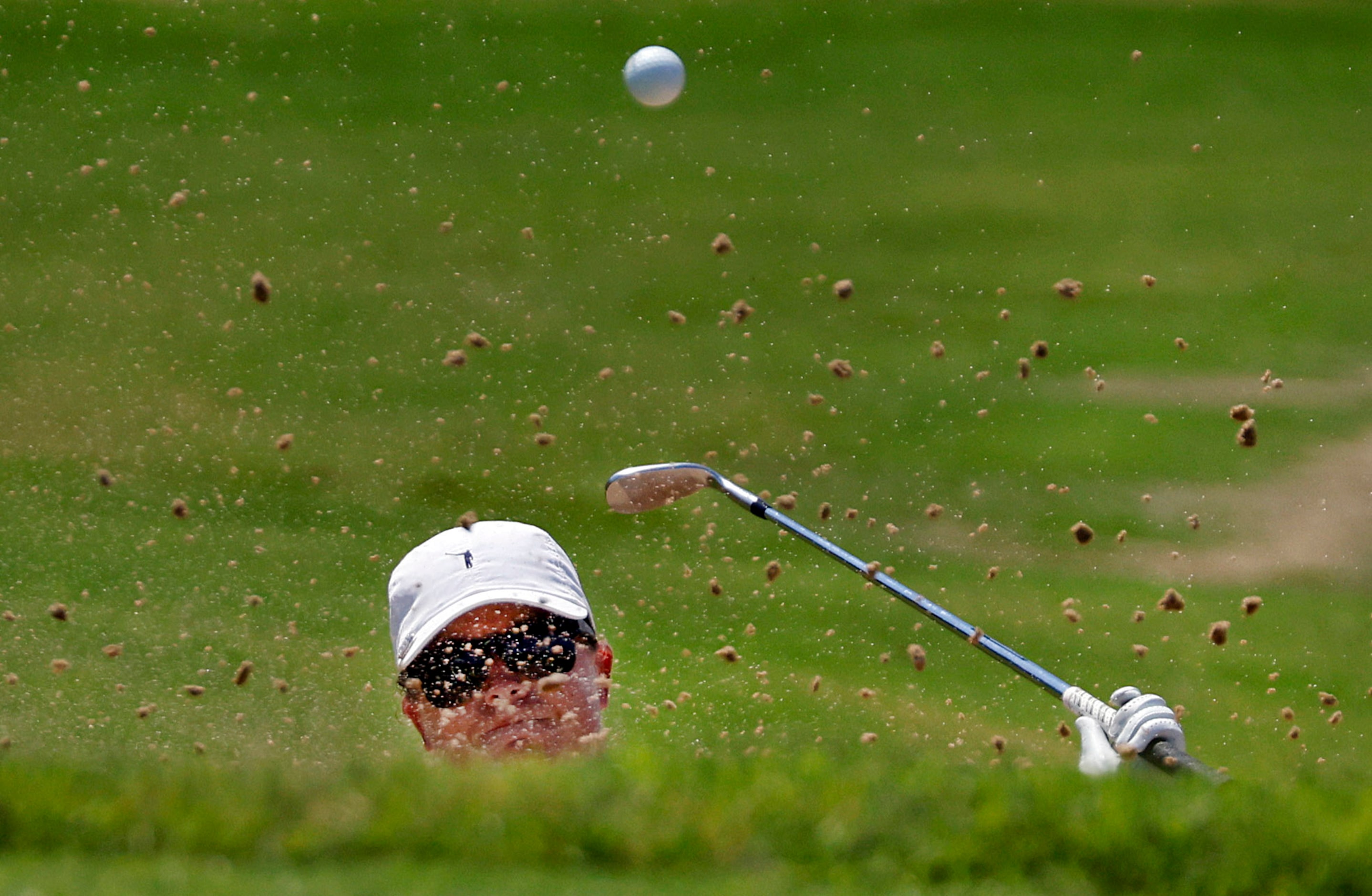 Professional golfer Lauren Coughlin attempts to hit her ball out of the green side bunker on...