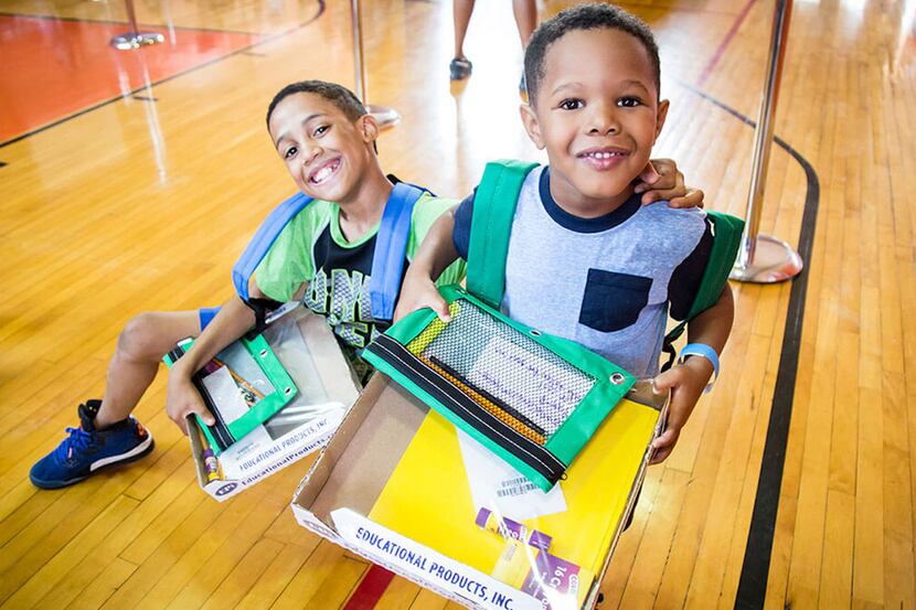 two young boys picking up school supplies in a gymnasium