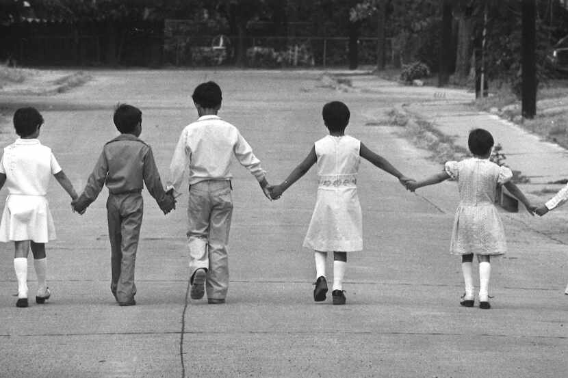 Children hold hands as they play in their Dallas neighborhood.