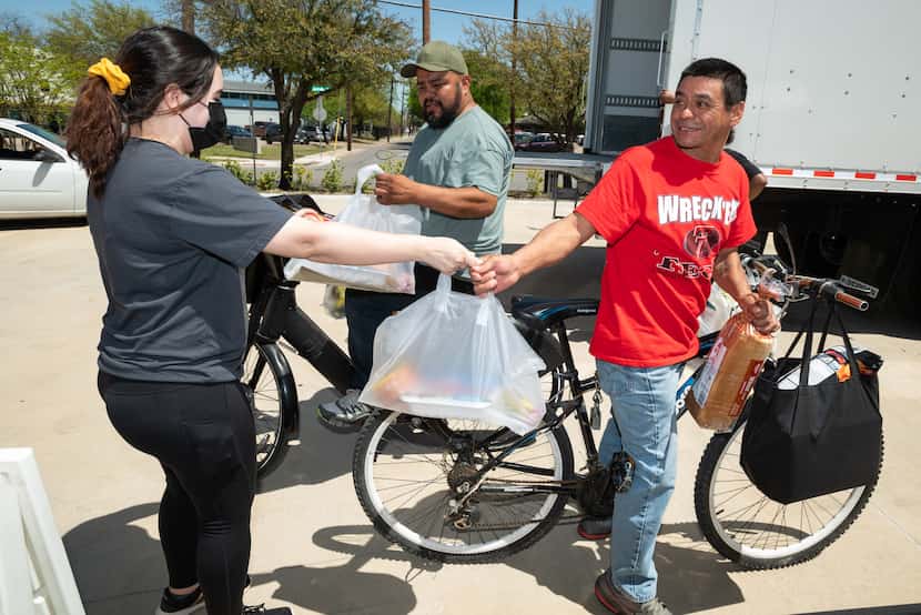 Goodr employee Gabriela Lopez handed bags of food to Rocky Munoz (center) and his friend...