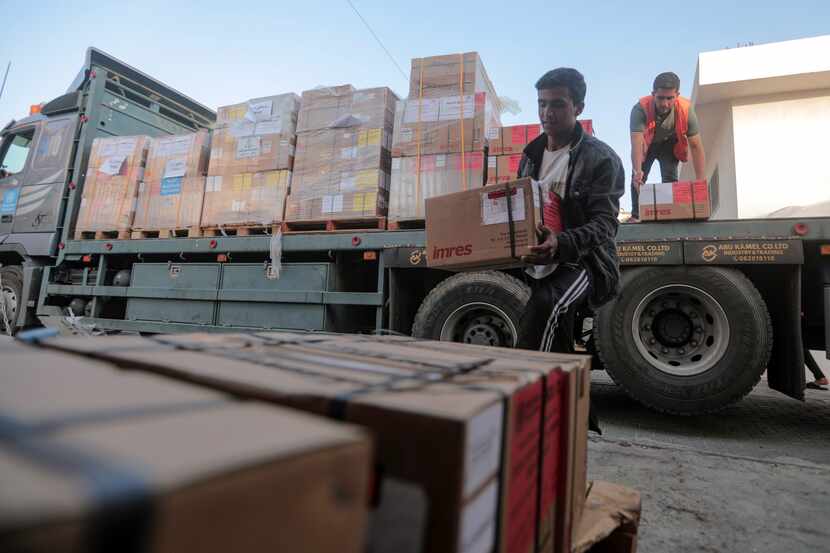 Palestinians unload boxes of medicine from a truck arrived at Nasser Medical Complex, as...
