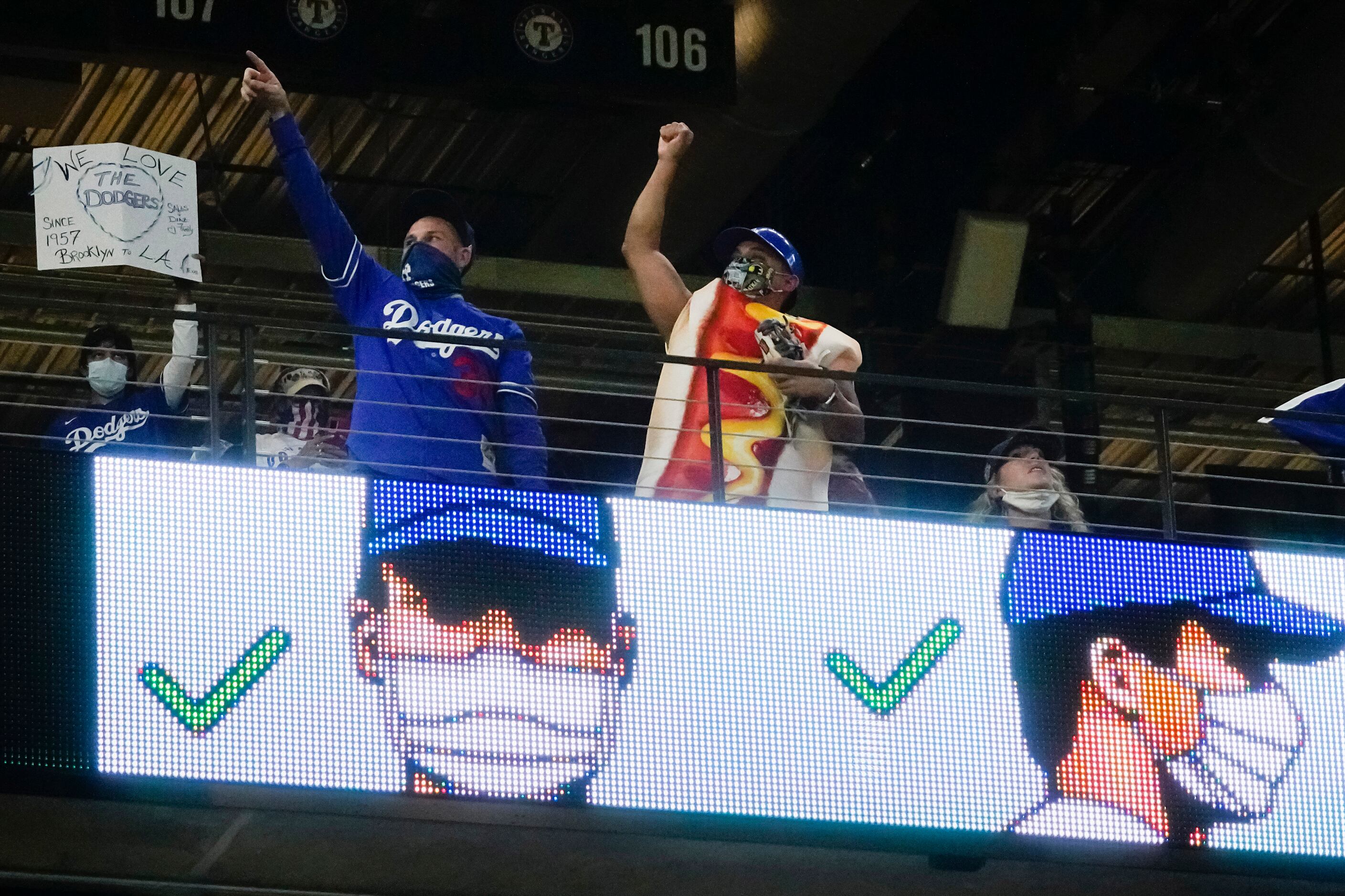 Los Angeles Dodgers fans, one dressed in a hot dog costume, cheer their team during the...