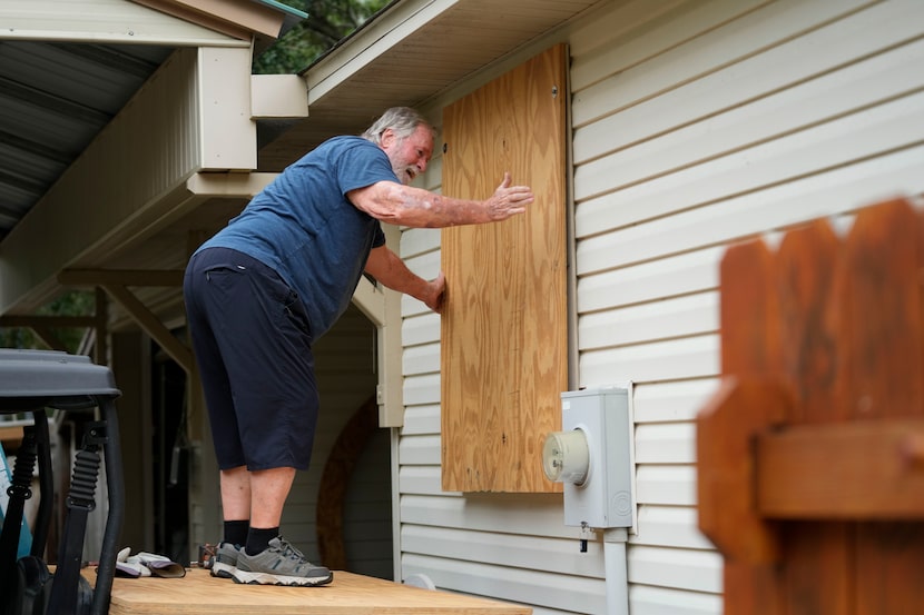 Dave McCurley boards up the windows to his home in advance of Tropical Storm Helene,...