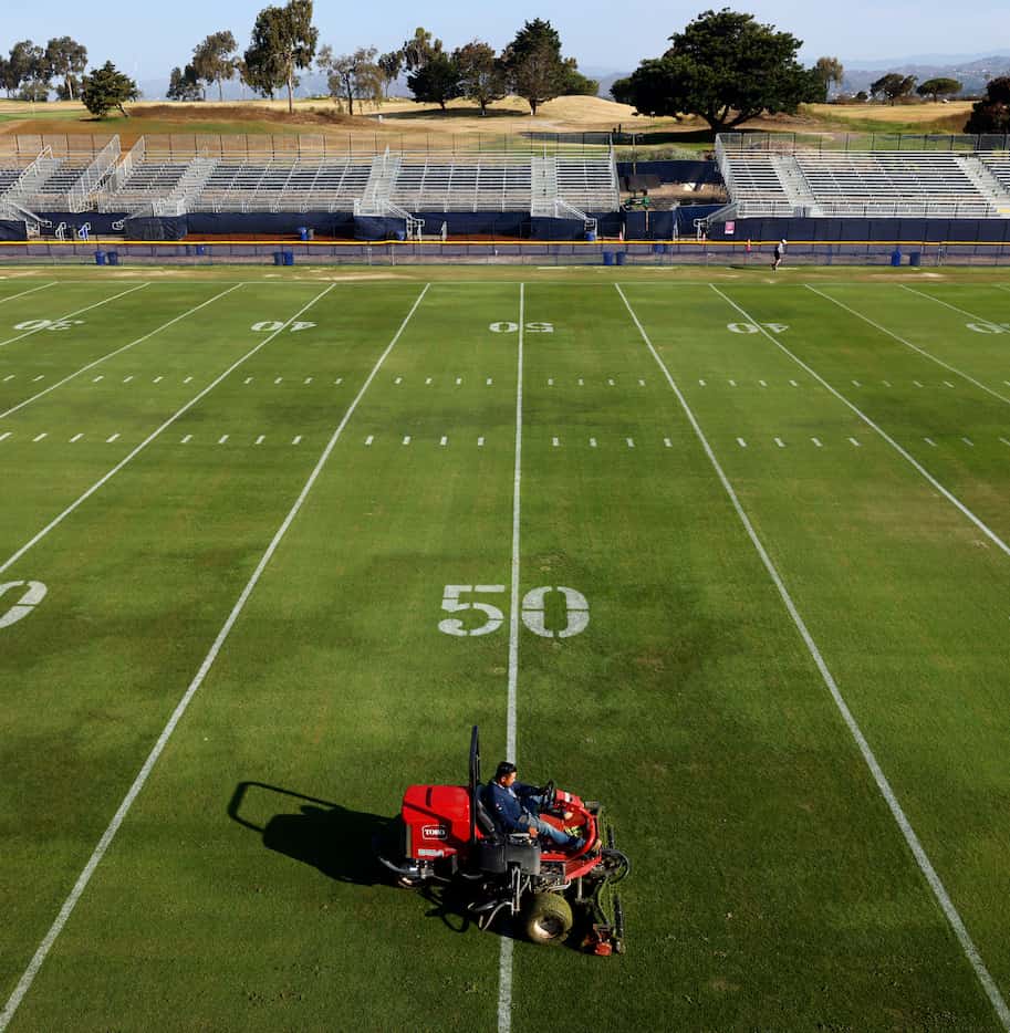 Grounds crewman Alberto Ortega cuts the grass fields in preparation for the Dallas Cowboys...