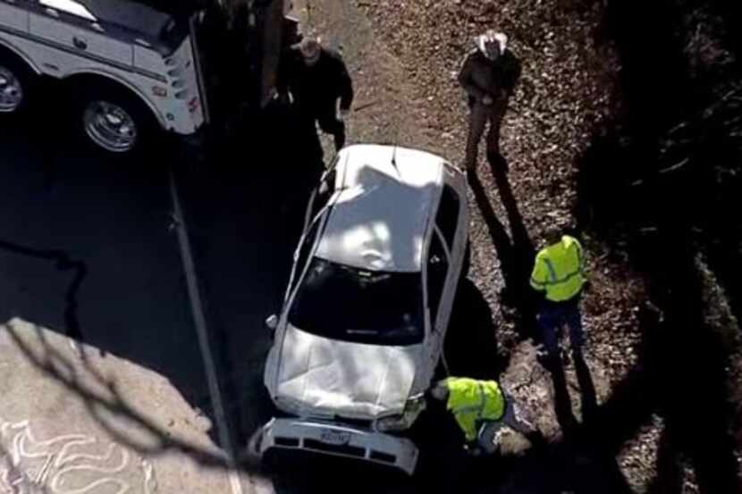 Authorities look over a vehicle found in a creek near Denton on Wednesday as they prepare to...