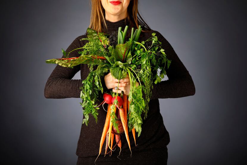 Rebecca White of A Pleasant Little Kitchen grasps a handful of vegetables she'll use to make...