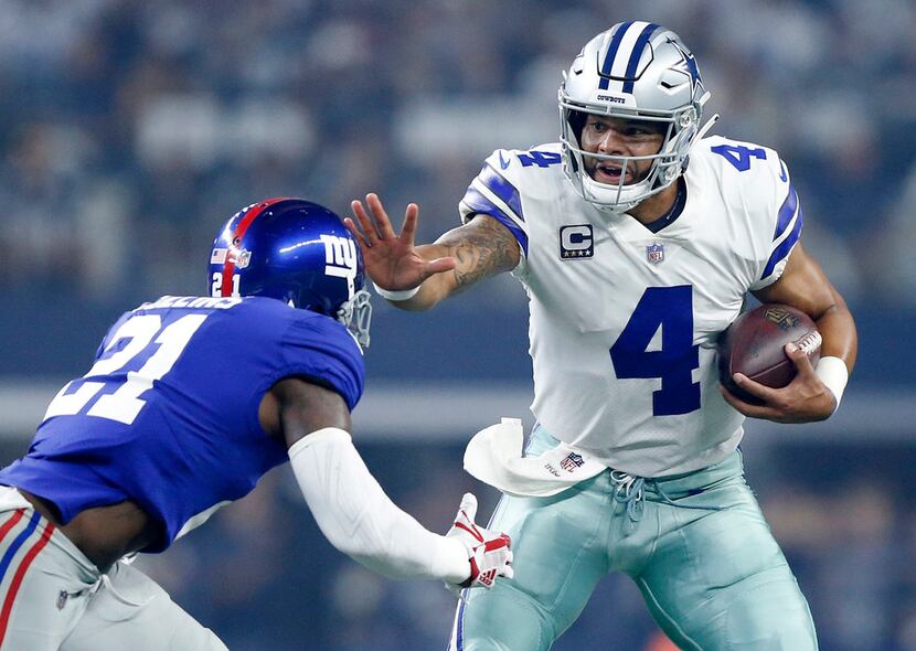 Dallas Cowboys quarterback Dak Prescott (4)gives a stiff arm to New York Giants defensive...