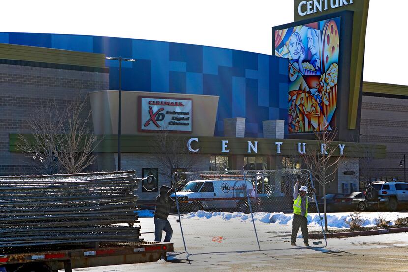 Workers with American Fence remove the fence from around the Century theater in Aurora,...