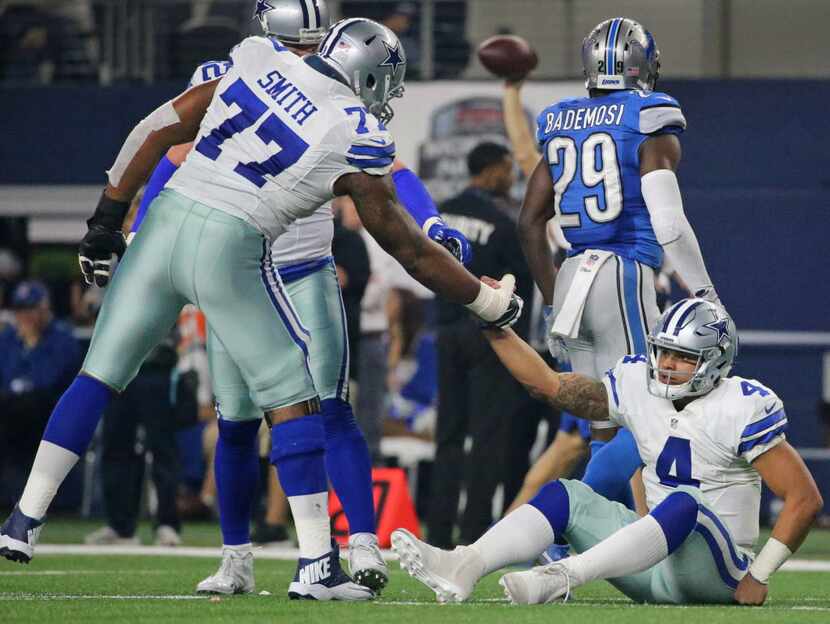 Dallas Cowboys tackle Tyron Smith (77) helps quarterback Dak Prescott (4) up from the turf...