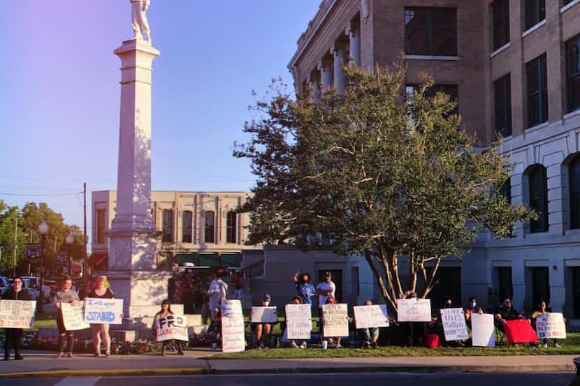 Protestors stand in front of the Confederate monument outside the Cooke County courthouse....