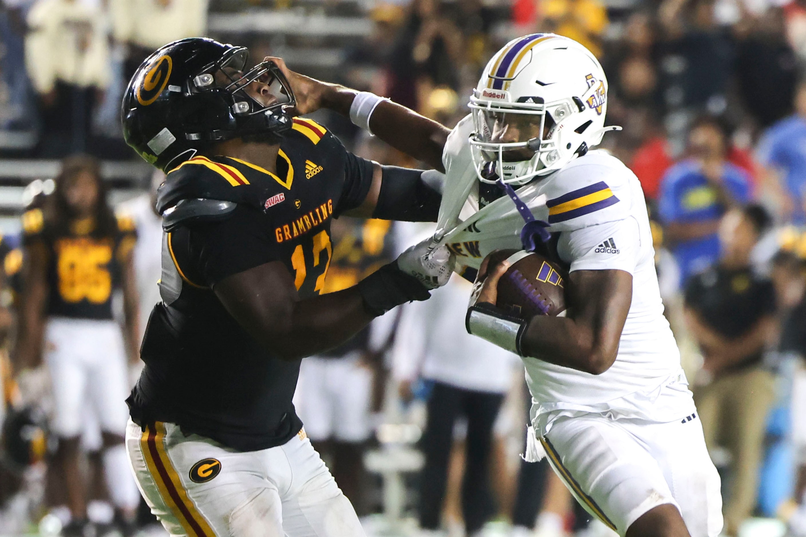 Grambling State defensive end Isaac Washington (left) gets a stiff-arm from Prairie View A&M...