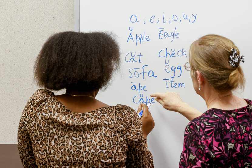 Adult education instructor Cynthia White (right) works on English vowel sounds with a...