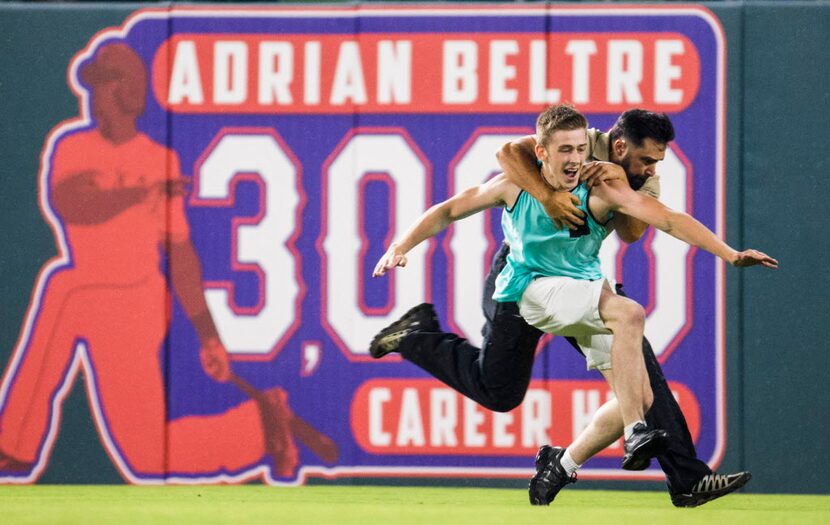 A fan is tackled by a security guard after he ran out on the field during the eighth inning...