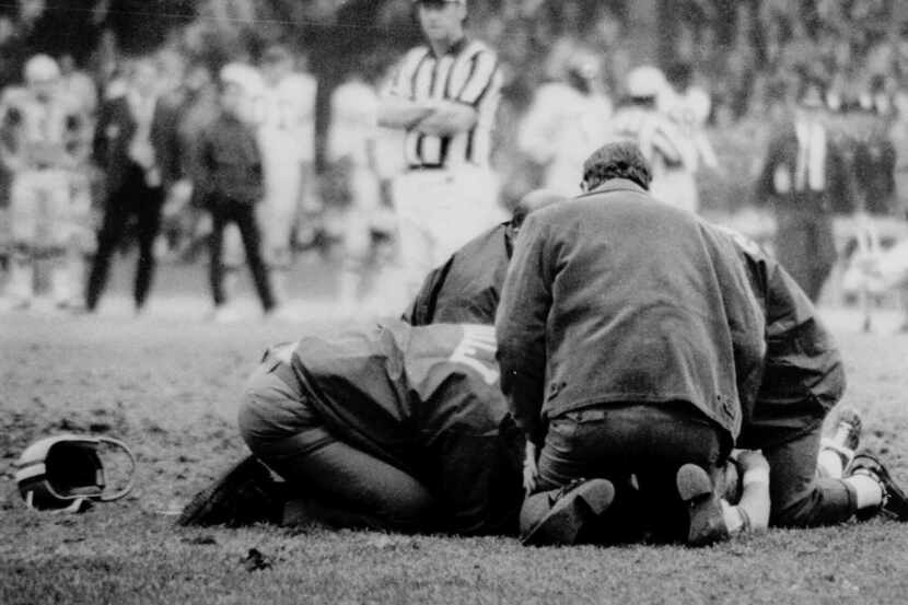 While the helmet of Chuck Hughes, Detroit Lions' wide receiver, lies near spot where he fell...