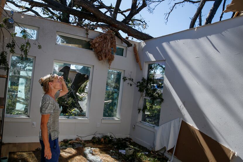 Debi Bird assesses damage in the study of her home, where the roof is missing, along...