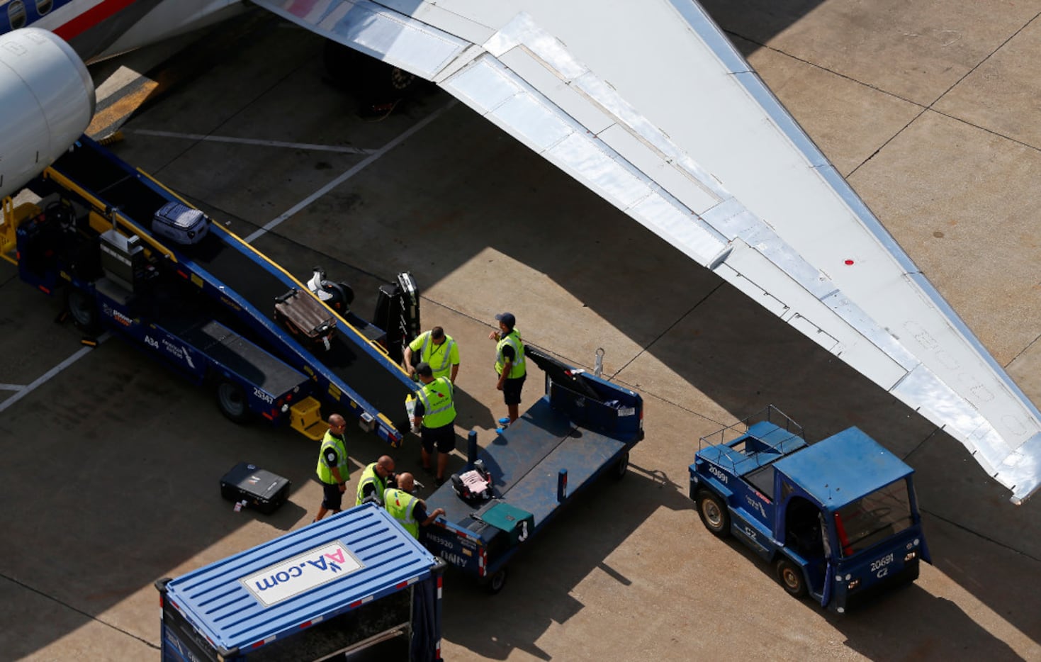 Members of the ground crew load bags onto an American Airlines jet at DFW International...