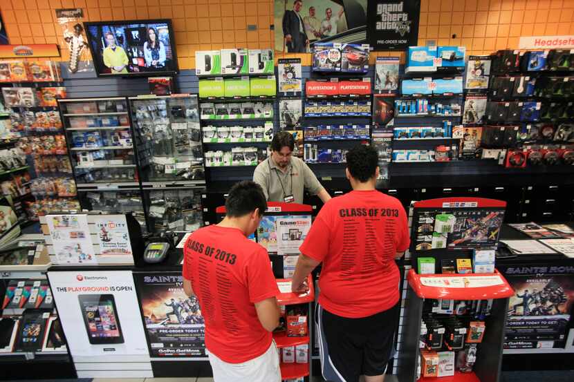 GameStop manager David Green, center, helps two customers at the store inside NorthPark...