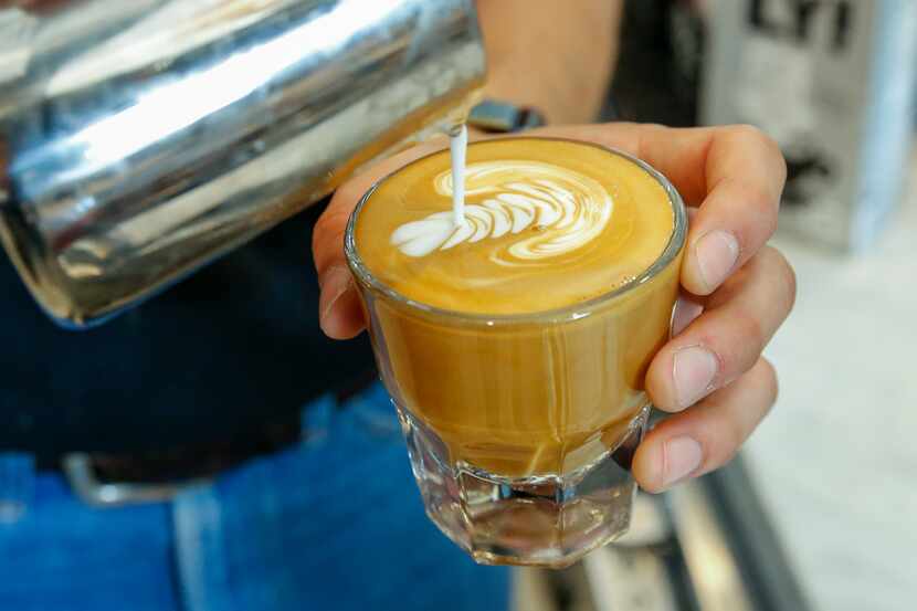 A barista adds milk while preparing a cortado at Ascension Coffee in the Design District on...