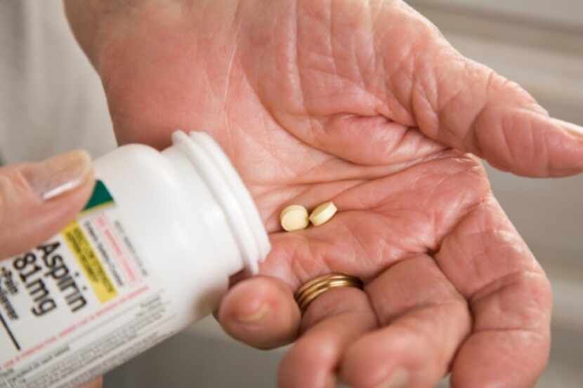 Un paciente toma pastillas de un contenedor de aspirinas.
