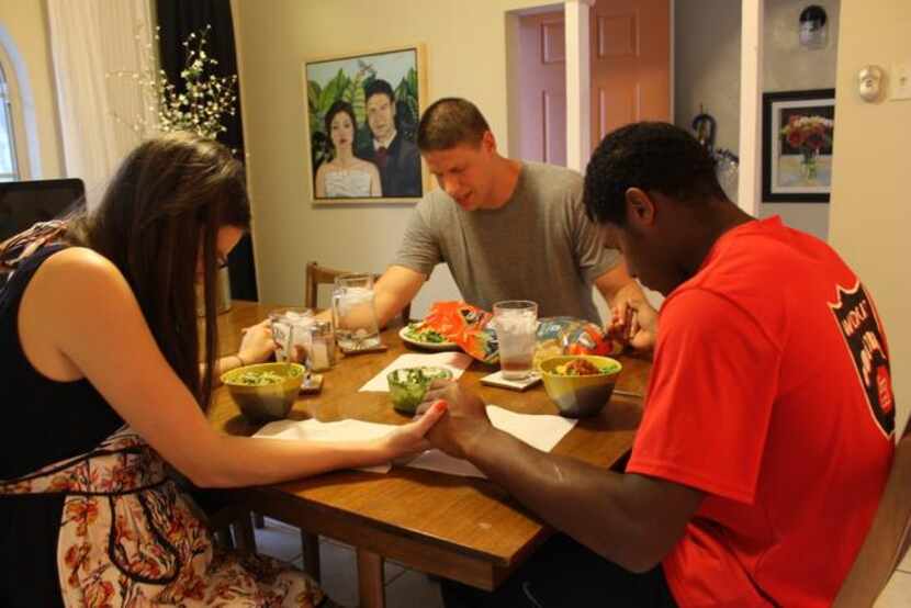 
Garza (middle) says a blessing before dinner with his wife, Sara, and Lake Highlands High...