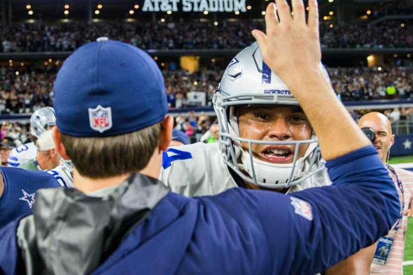 Dallas Cowboys quarterback Tony Romo (9) pats the helmet of quarterback Dak Prescott (4)...