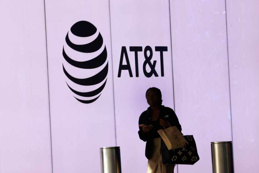 A woman walks by an AT&T logo at AT&T Discovery District in downtown Dallas,Thursday, Feb....
