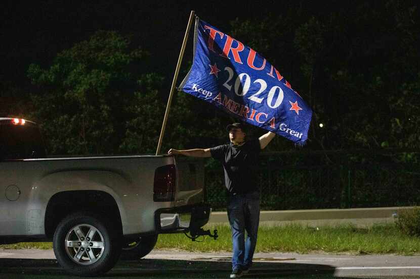 A man who declined to provide his name stands by a flag expressing support for former...