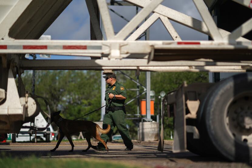 A U.S. Border Patrol agent with a K-9 checks incoming cars at a checkpoint in Falfurrias,...