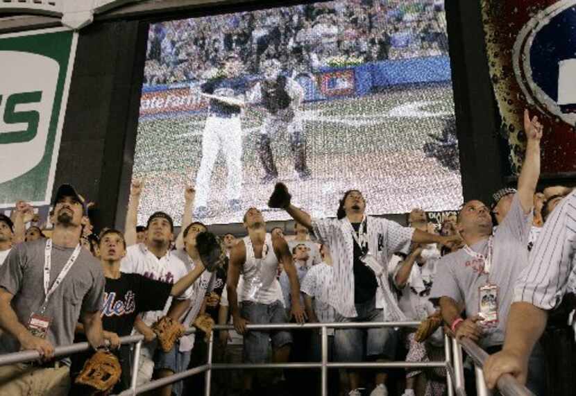 Fans in the bleacher seats watch a home run by Texas Rangers' Josh Hamilton (on screen)...