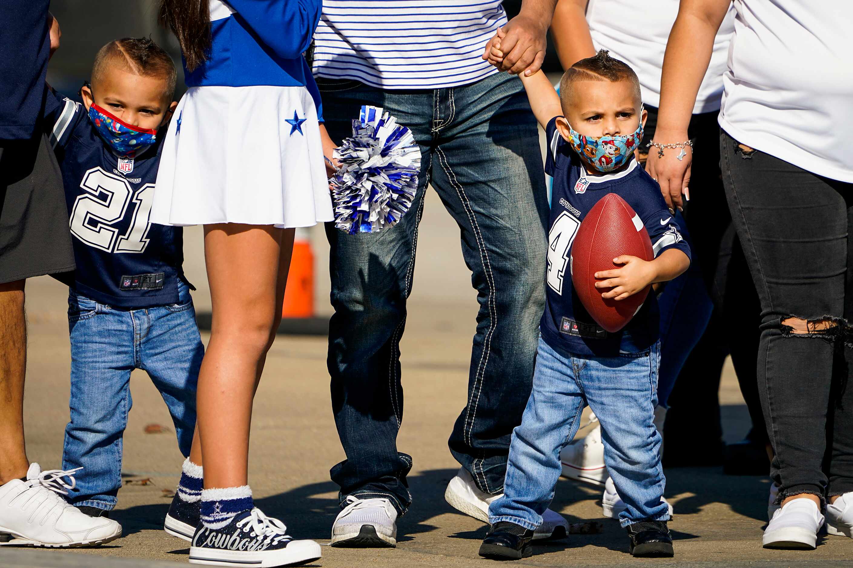 Jayce Sartuche, 3, from Victoria, Texas, clutches a football as he heads into the stadium...