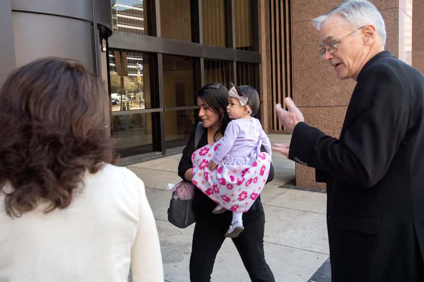 Lucia Mejia, carrying her 19-month-old daughter Teresa, is accompanied by Auxiliary Bishop...