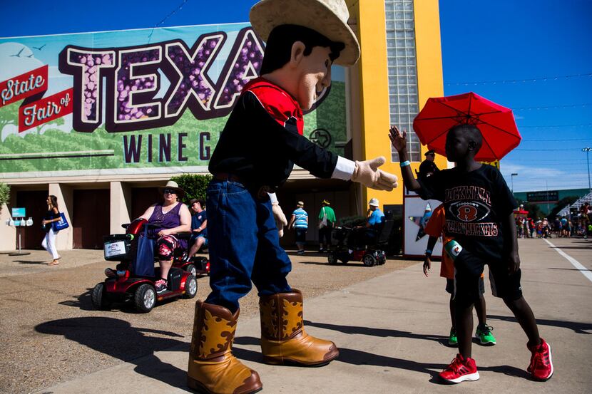Big Little Tex gets a high-five from Benjamin Smith, 8, at the State Fair of Texas on Oct....