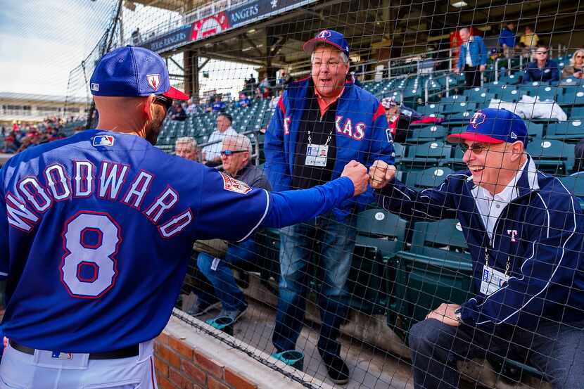 Texas Rangers manager Chris Woodward gest a fist bump from Ken Hall before a spring training...