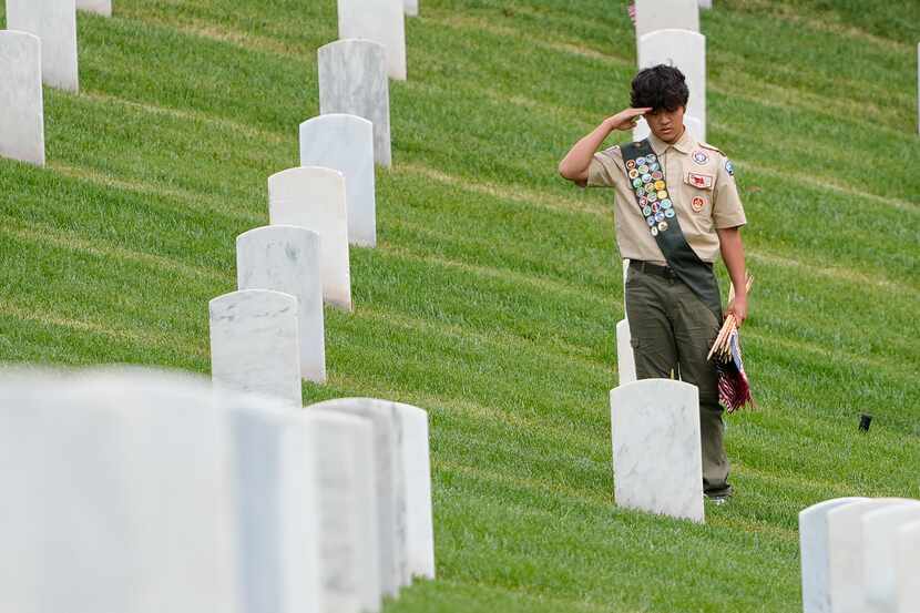 A Boy Scout salutes at the grave of fallen soldiers after placing flags at the Los Angeles...