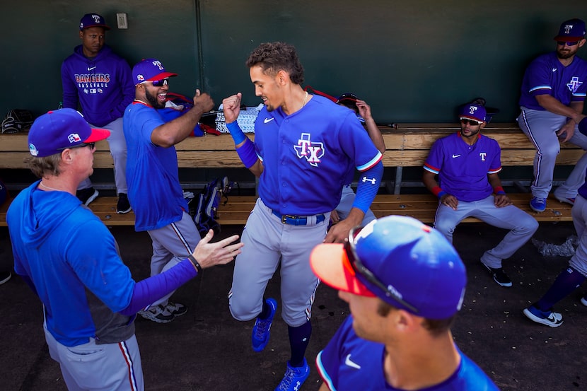 Texas Rangers first baseman Ronald Guzman (center) dances in the dugout with shortstop Elvis...