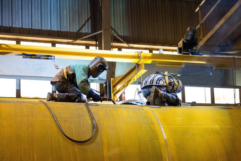 Welders for Dallas-based Trinity Industries work on a crude oil tank car at the company's...