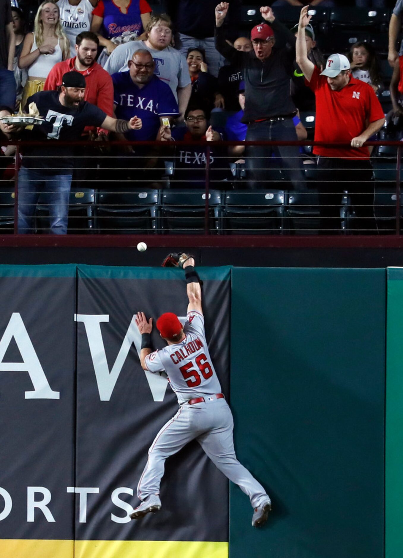 Fans watch as a ball that bounced off the top of Los Angeles Angels right fielder Kole...