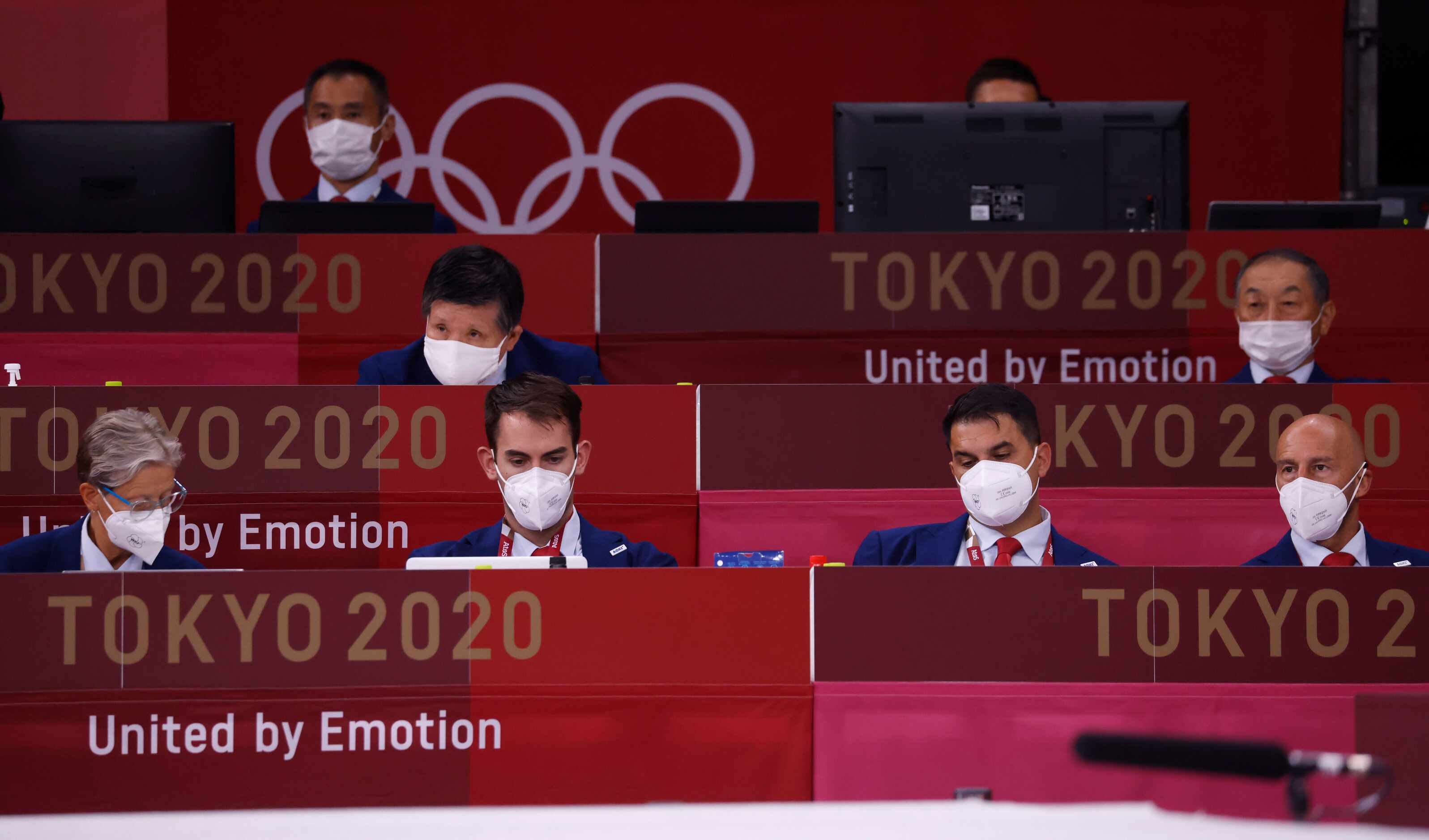 Masked officials look over the bouts during the karate men’s kumite -75kg elimination round...