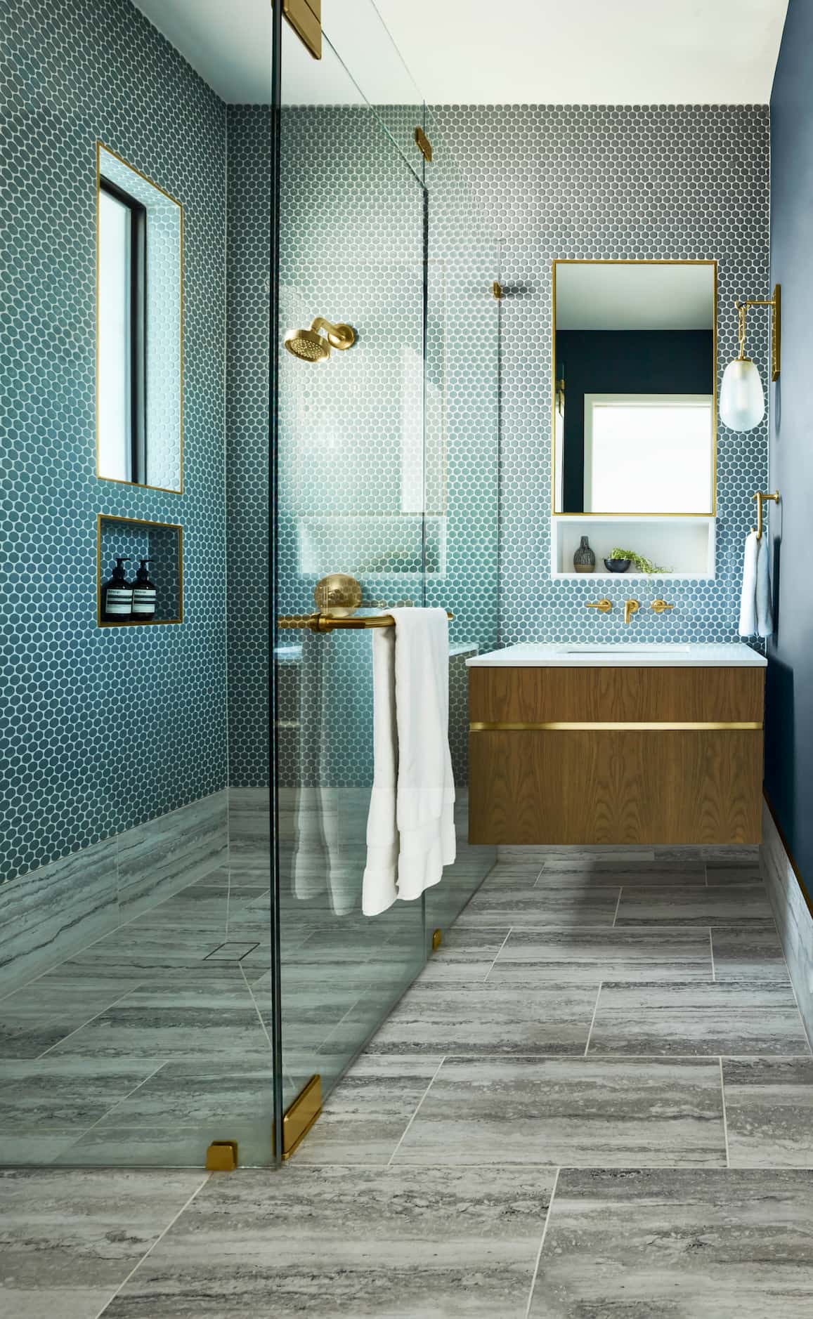 Azure-colored bathroom with blue penny tile on the walls and gray tile on the floor,...