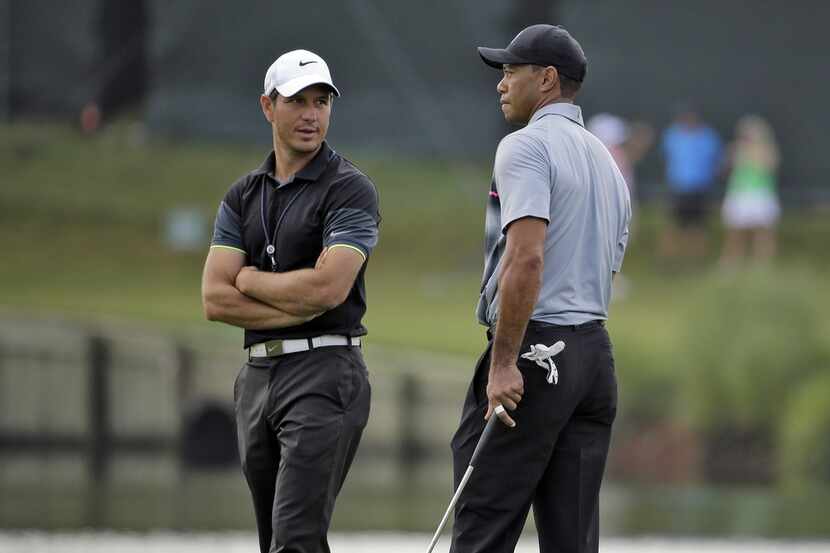 FILE - In this May 6, 2015, file photo, Tiger Woods, right, talks with swing coach Chris...