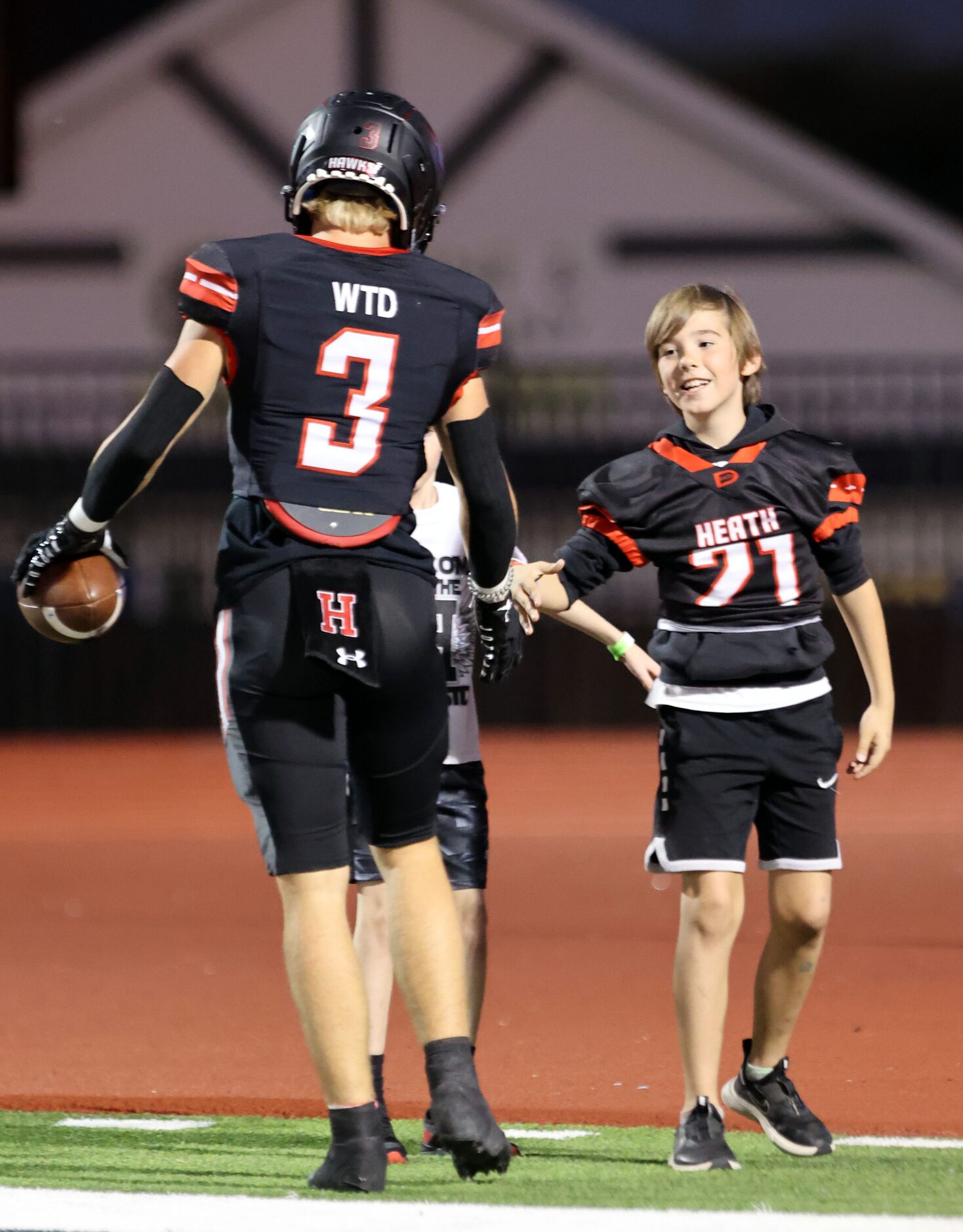 Rockwall Heath’s Peyton Wingfield (3) slaps hands with kids in the end zone after making a...